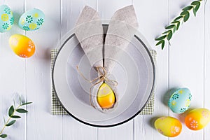 Spring festive Easter table setting with bunny ears linen napkin and kitchen cutlery. Flat lay,