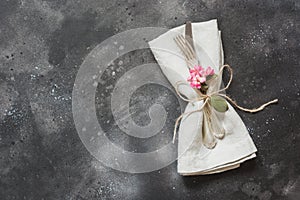 Spring festive table setting with cutlery and lilac flower on black stone table. Copy space. Flat lay.