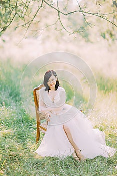 Spring field composition of the woman in the long white dress sitting in the old modern chair. photo