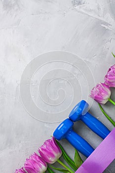 Spring flatlay sports composition with blue dumbbells and purple