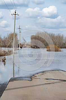 Spring flood on the river. Flood of river. Flooding of road with water.