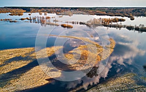 Spring flood rural landscape. Trees, meadow, bushes, fields, country road under High Water inundation. Sky, clouds reflection in