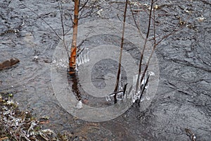 Spring flood. Rushing water in the river, top view. Dark ferrous water rushes in the stream. A yellow-white foam