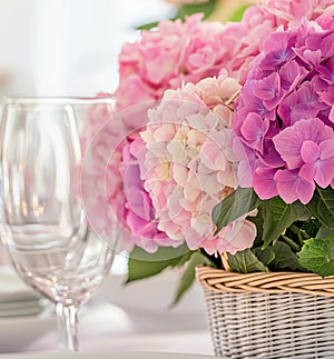 Spring floral arrangement of pink hydrangeas in a wicker basket, creating a romantic and festive table setting photo