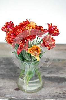 Spring flowers. Bouquet of Red tulips in Glass vase on brown wooden background. Mother's Day and Valentines Day background