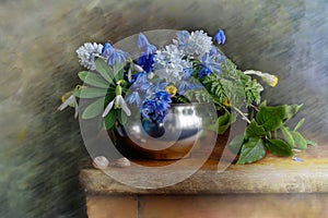 Spring flowers.Bouquet of snowdrops in a metal vase on a blue background