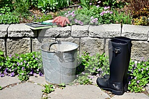 Spring flowers in early season garden with tools and weeding pail ready for garden maintenance