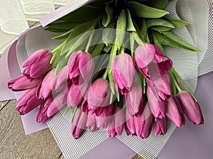 Spring flowers on a pink background, tulips. Bouquet of pink tulips in paper packaging