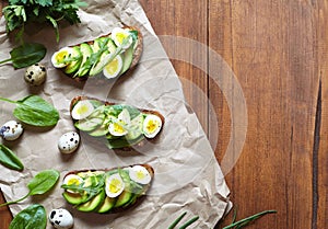 Spring food. A whole grain bread toast sandwich with avocado, spinach, guacamole and quail eggs on parchment.
