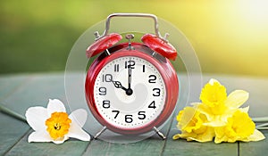 Spring forward, daylight savings time concept, alarm clock and easter flowers