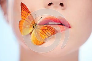 Spring-fresh skin. A butterfly sitting on the side of a womans mouth.