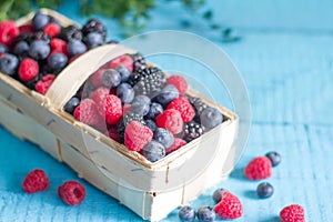 Spring fruits berries in the punnet on blue wooden boards