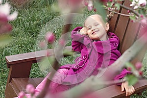 Spring garden baby. Little girl in spring garden near flowers.