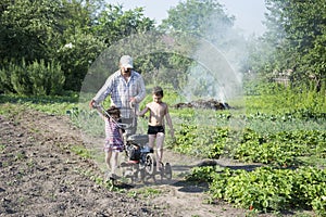 Spring in the garden man plowing land motor-block small son and