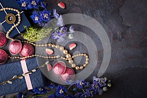 Spring gift with candy, pearl necklace and flowers on a blue stone background