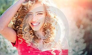 Spring girl with curly hair smiling. Beauty hair Salon. Beauty girl with long and shiny curly hair. Trendy haircuts