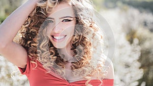 Spring girl with curly hair smiling. Beauty hair Salon. Beauty girl with long and shiny curly hair. Trendy haircuts