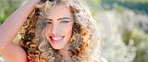 Spring girl with curly hair smiling. Beauty young woman enjoying nature in spring garden. Banner spring design