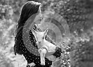 Spring girl with lamb. Goat milk. Sensual woman with goat. Animal, countryside. Beauty young woman enjoying nature in