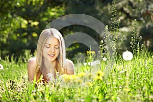 Spring girl lying on the field of dandelions