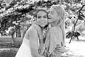 Spring girls in flowers. Outdoor portrait of young beautiful happy smiling female couple posing near flowering tree.