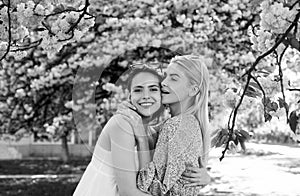 Spring girls in flowers. Outdoor portrait of young beautiful happy smiling female couple posing near flowering tree.