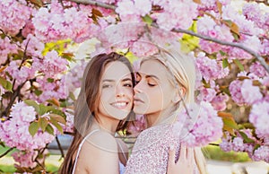 Spring girls. Lesbian couple kissing. Beautiful spring sexy young woman with sakura flowers. Sensual kiss. Lgbt.