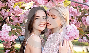 Spring girls. Lesbian couple kissing. Beautiful spring sexy young woman with sakura flowers. Sensual kiss. Lgbt.