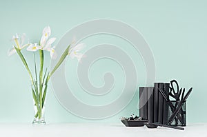 Spring green mint menthe interior of office with black stationery, books, fresh white iris bouquet  in transparent glass vase. photo