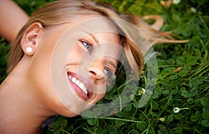 Spring, happy and field with woman on grass in nature for calm, smile and peace. Park, flowers and relax with face of