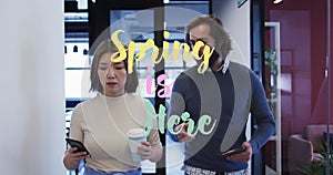 Spring is here text over diverse male and female office colleagues discussing in corridor at office