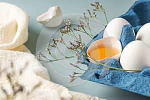 Spring holiday Easter concept. Broken egg with yolk in the shell. Close-up of fresh chicken eggs in eco-packaging on a blue