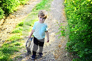 Spring holiday. Sunny weather. Small child with toy in shopping bag. summer. Little boy child in green forest. Happy kid