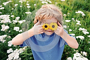Spring kid. Funny little boy with daisy in eyes.