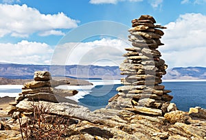 Spring landscape of Baikal Lake with big cairns on a rocky promontory