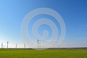 Spring landscape with blue skies and green, field and wind farm