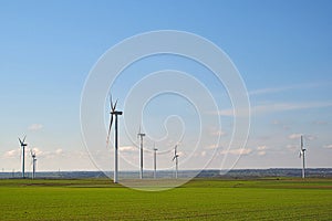 Spring landscape with blue skies and green, field and wind farm