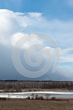 Spring landscape. Early spring. A lake with ice and beautiful thundery skies.