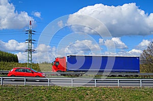Spring landscape with a highway and a red car traveling against the red truck
