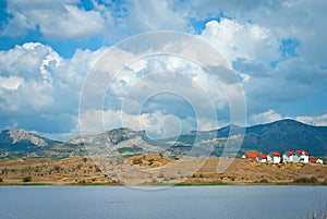 Spring landscape with houses, mountains and clouds in sky