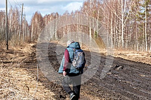 spring landscape with muddy swamp, forest road, spring, lonely traveler on a dirty wet road