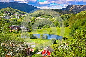 Spring Landscape with Overview of A Tranquil Valley with Green Meadows, A Pond and Colorful Farm Houses in The Sunlight