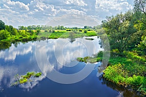 Spring landscape with river and clouds on the blue