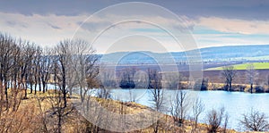 Spring landscape with river, trees by the river and plowed field on a sunny day