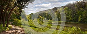 Spring landscape - road near the pine forest, next to a pond