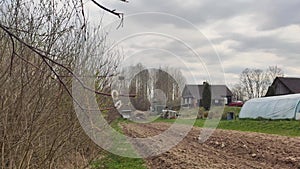 Spring landscape. Rural house building and small greenhouse