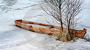 spring landscape with a wooden boat frozen in ice, abandoned boats on the shore of the lake, late winter, spring in nature