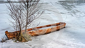 spring landscape with a wooden boat frozen in ice, abandoned boats on the shore of the lake, late winter, spring in nature