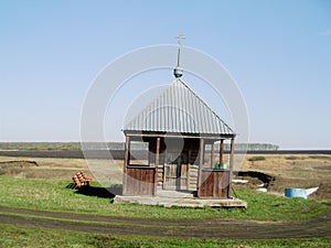 Spring landscape with wooden chapel in the field