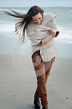 Spring lifestyle fashion portrait of young stylish woman walking on a sea beach